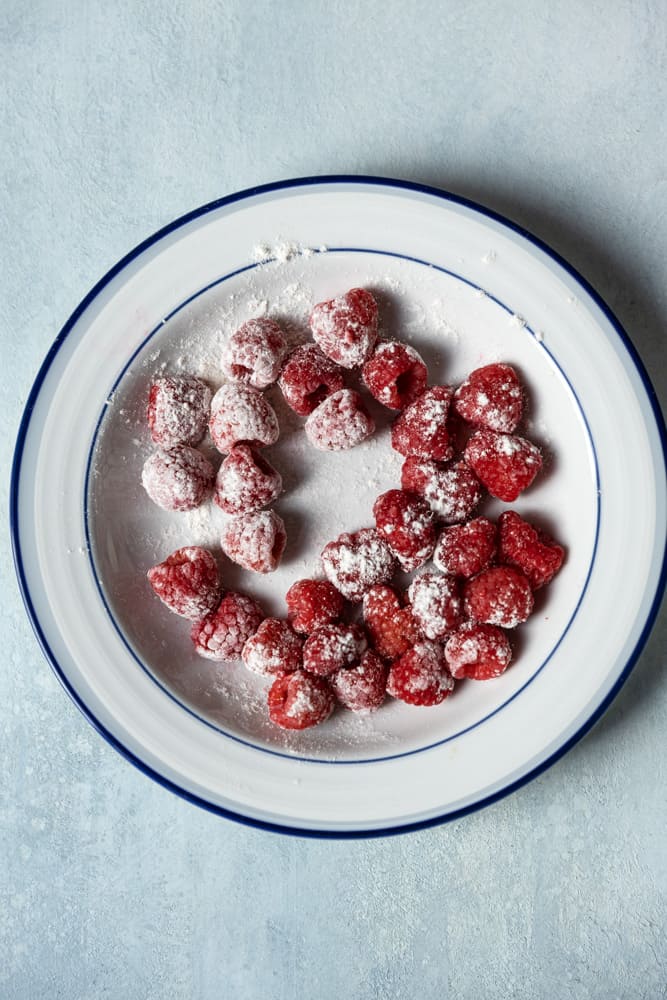 Raspberries coated with flour in a bowl.