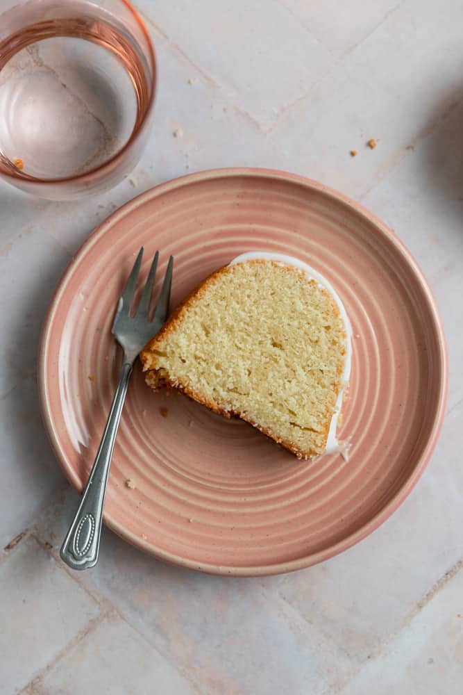 A slice of vanilla bundt cake on a pink plate next to a fork.