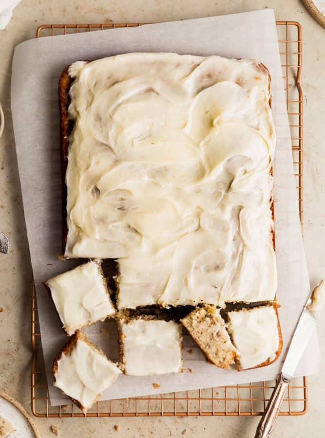 Banana sheet cake topped with cream cheese frosting and cut into 4 pieces.