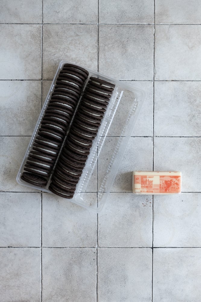 Oreos and butter on a gray tiled surface.