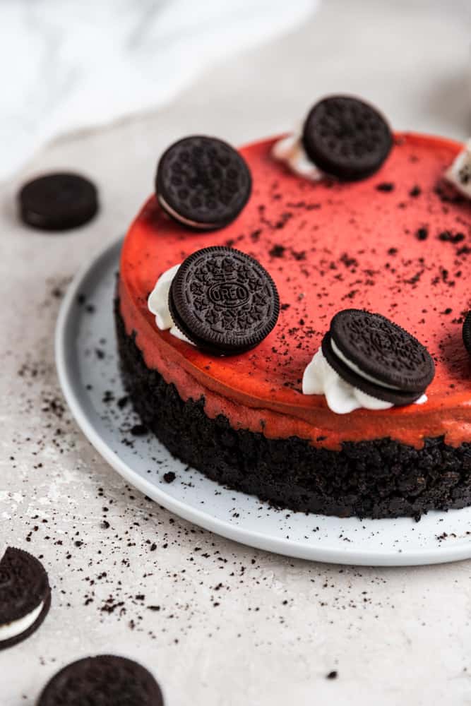 A red velvet oreo cheesecake garnished with oreos on a white plate.