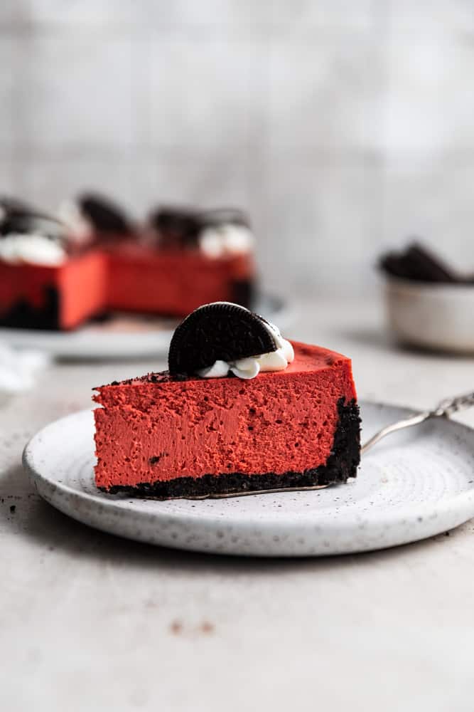 A slice of red velvet cheesecake on a white plate.