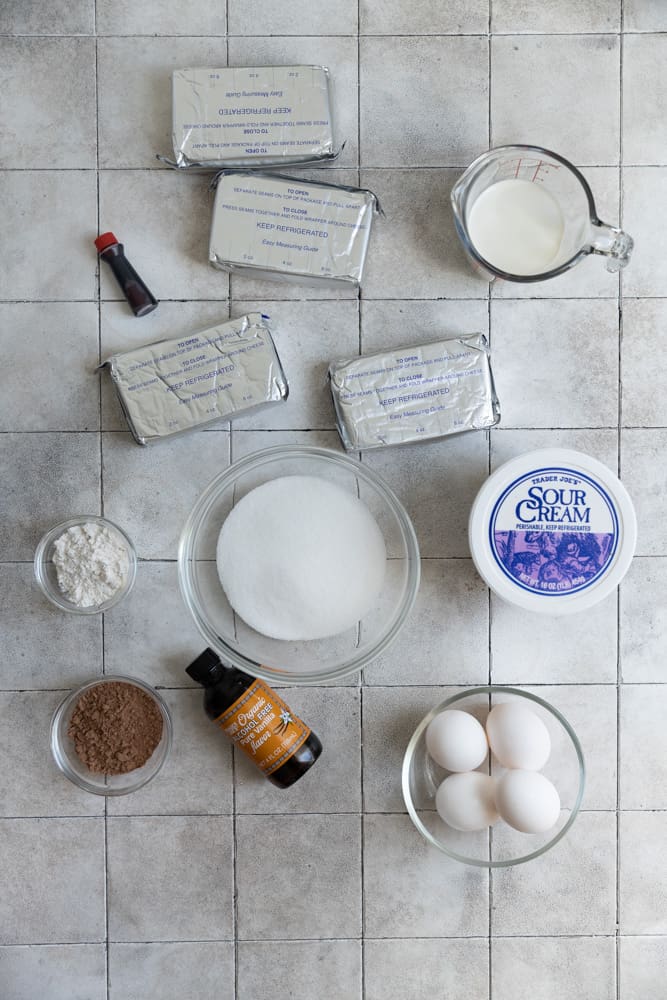 Ingredients for red velvet cheesecake on a tiled surface.