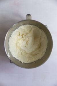 A mixture of butter, sugar, and eggs in a mixing bowl.