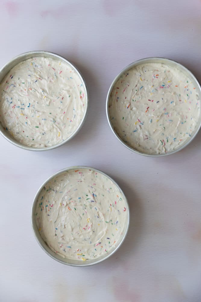 Cake batter divided into 3 baking pans.