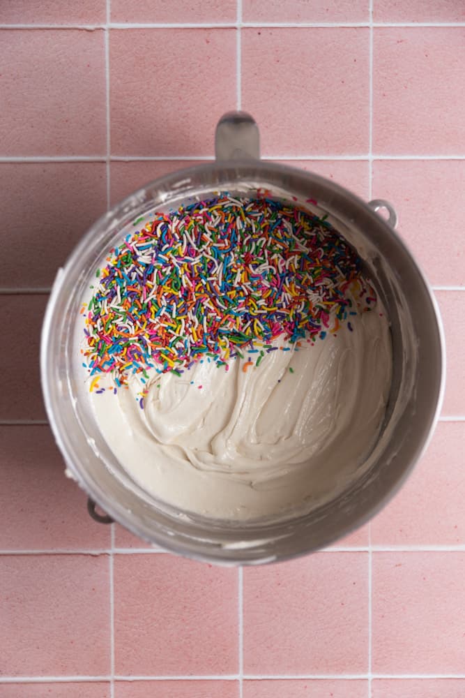 Vanilla cake batter topped with sprinkles in a mixing bowl.