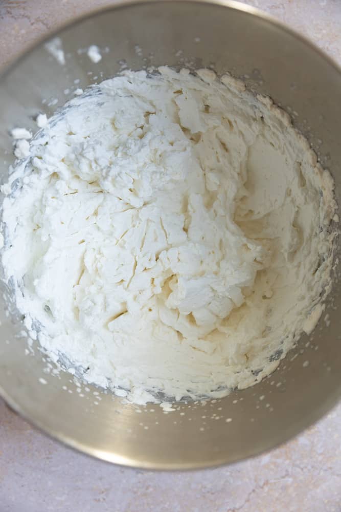 Curdled whipped cream in a mixing bowl.