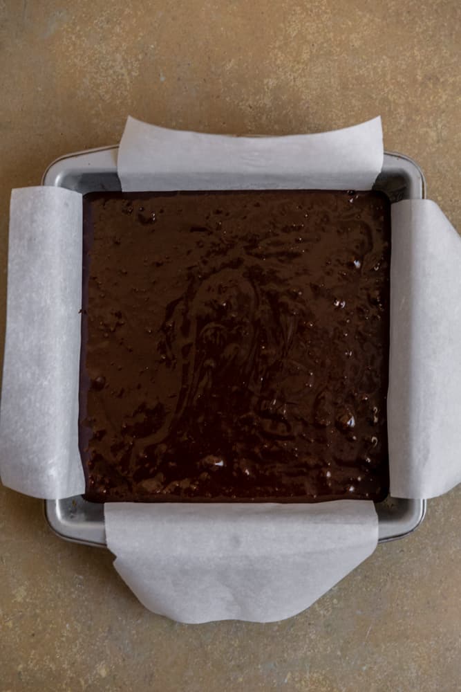 Dairy free brownie batter in a pan lined with parchment paper.