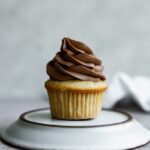 A vanilla cupcake topped with chocolate frosting.