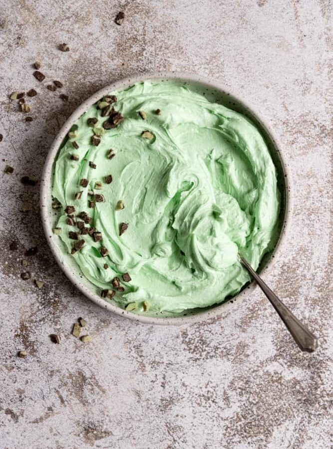 A bowl of mint frosting top with chopped andes mints.