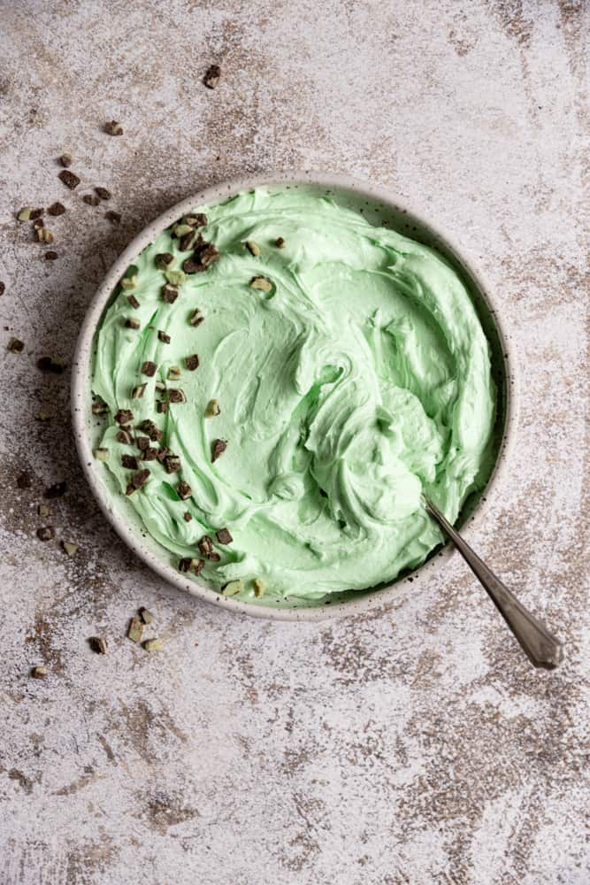 A bowl of mint frosting top with chopped andes mints. 