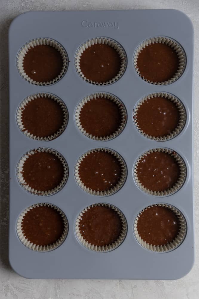 Chocolate cupcake batter in a muffin tin.