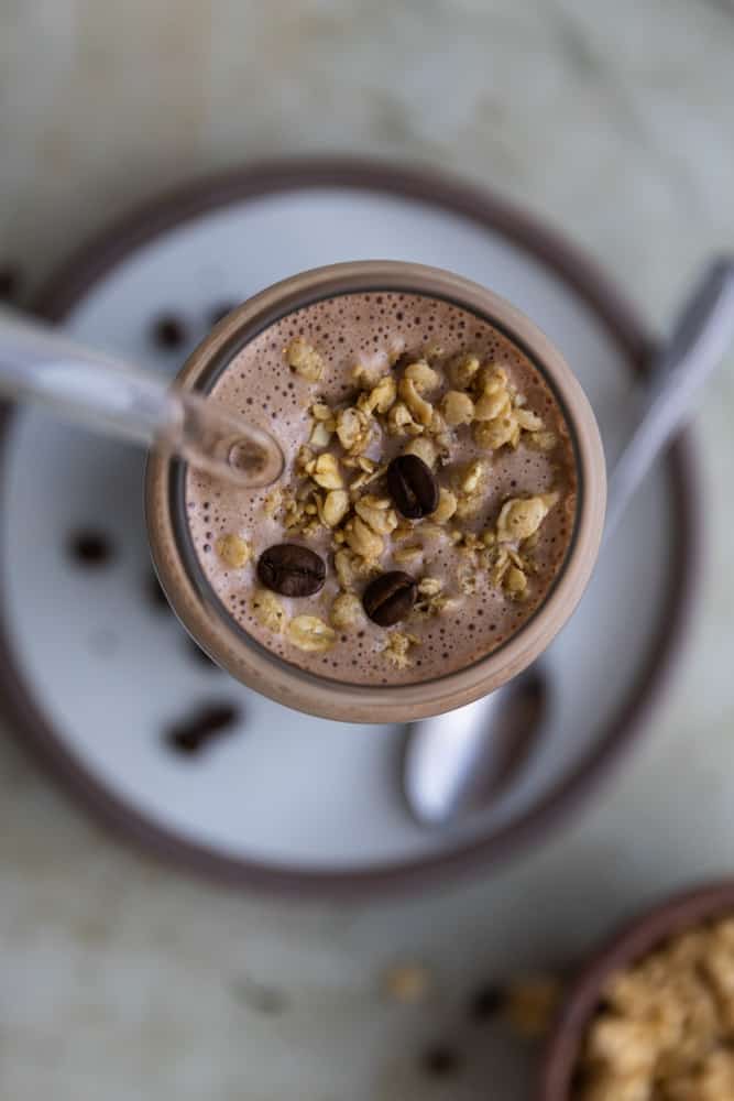 The top of a coffee smoothie topped with granola and chocolate chips.