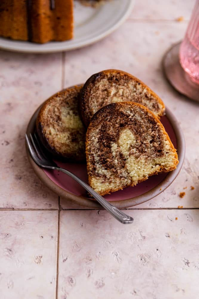Three slices of marble bundt cake on a pink plate. 