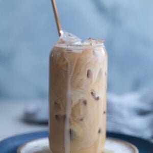 Vanilla iced coffee in a glass cup on a white plate.
