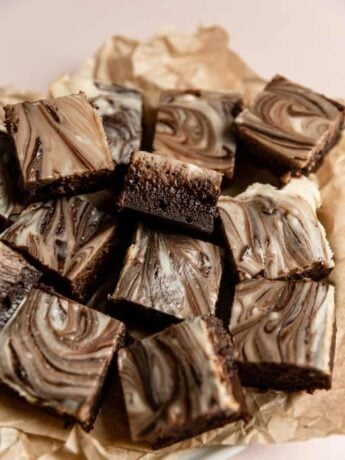 Cream cheese brownies served on brown parchment paper.