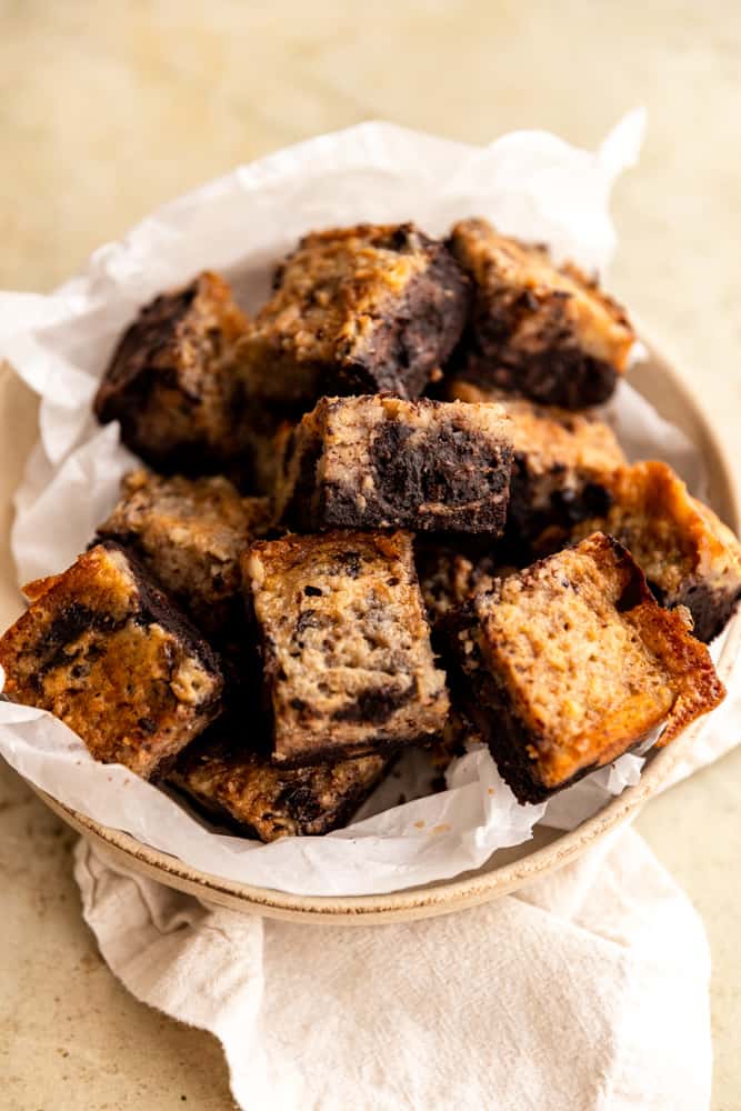 Banana Bread brownies layered onto a parchment lined plate. 