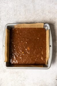 Banana brownie batter in a parchment lined brownie tin.