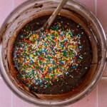 Brownie batter with sprinkles on top in a glass bowl.