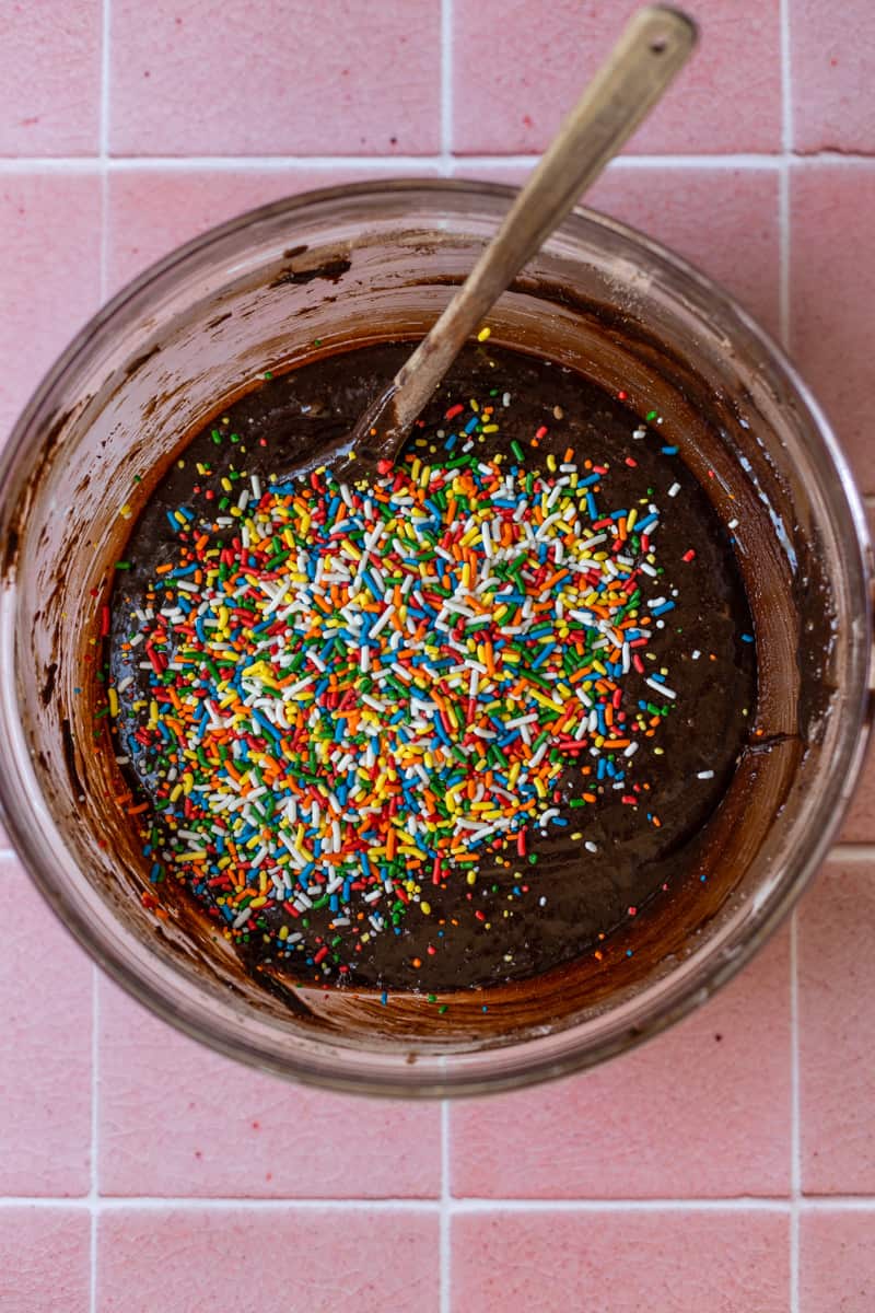Brownie batter with sprinkles on top in a glass bowl.