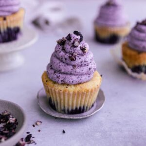 A blueberry cupcake topped with blueberry buttercream frosting.