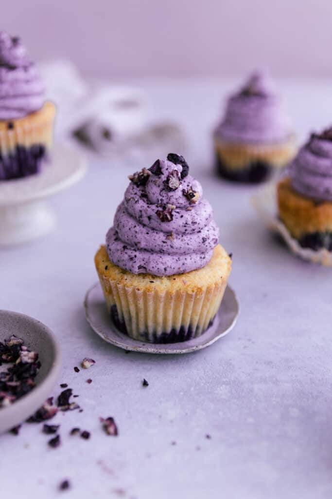 A blueberry cupcake topped with blueberry buttercream frosting.