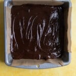 Brownie batter in a 8x8 parchment lined tray.