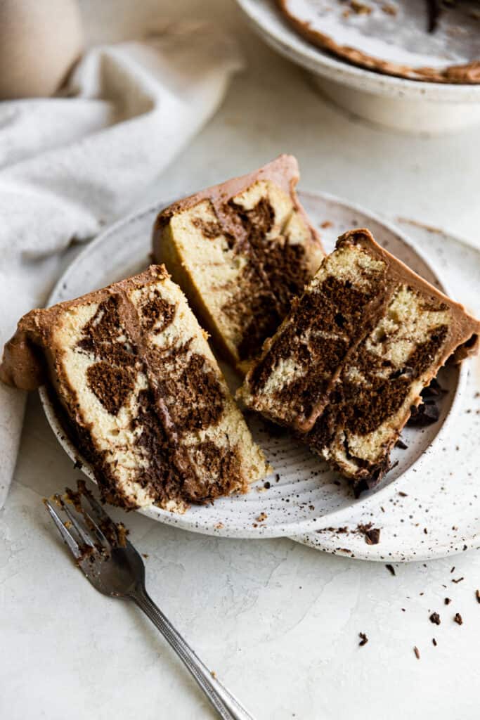 3 slices of marble cake stacked on a white plate.