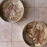 2 cake pans swirled with marble cake batter.