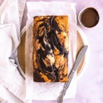 A marble loaf cake layered on parchment paper on a plate.