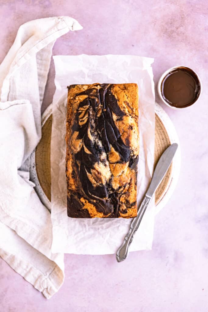 A marble loaf cake layered on parchment paper on a plate.