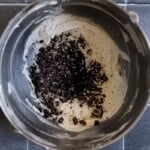 Crushed oreos in a bowl of frosting.