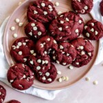 Red velvet cookies with white chocolate chips on a pink plate.