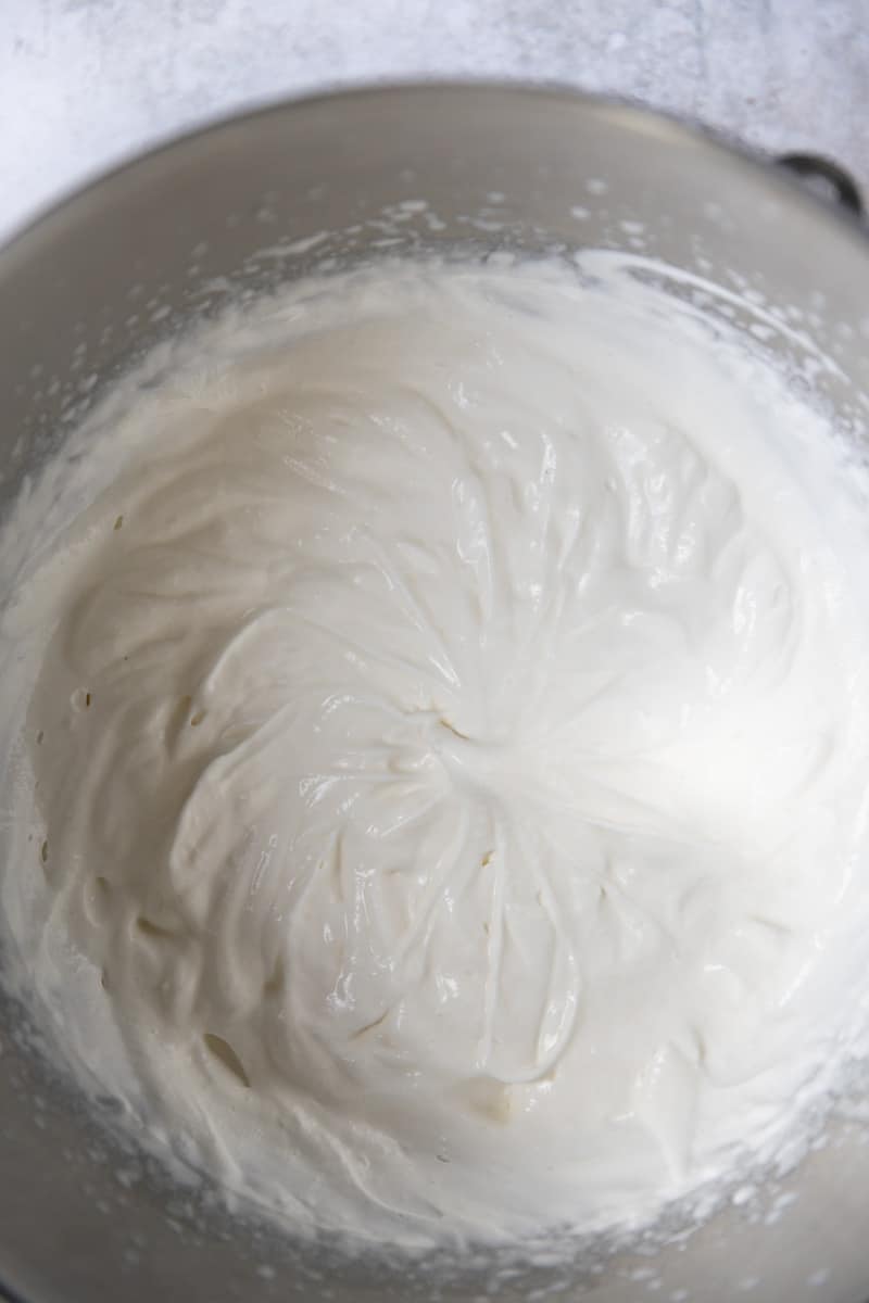 Soft peaks of whipped cream in a mixing bowl.