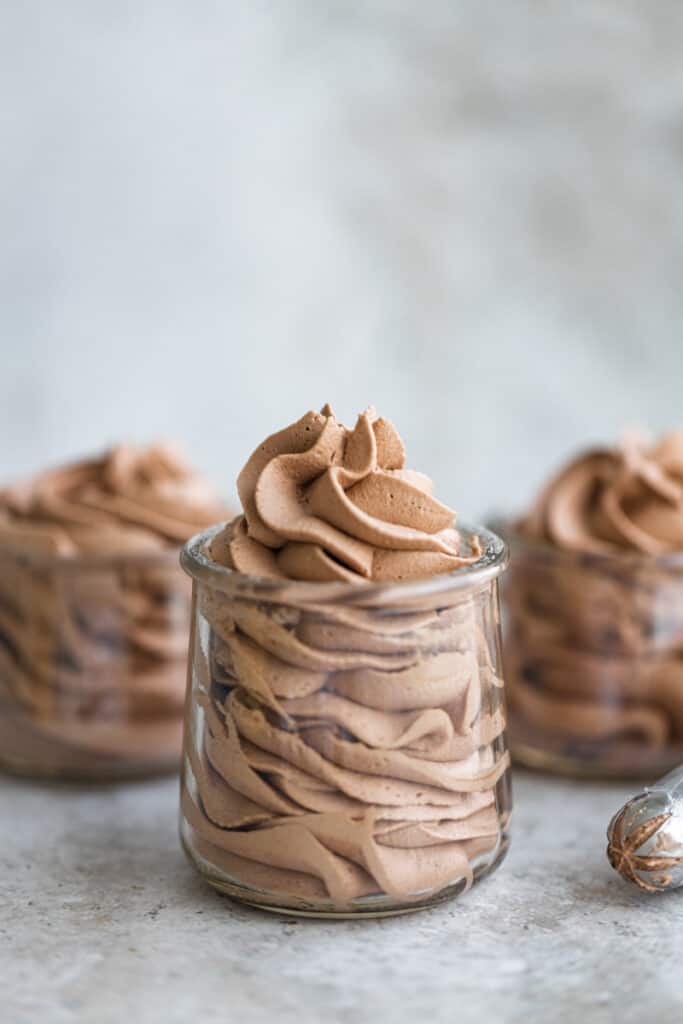 Whipped chocolate frosting in 3 small glass jars.