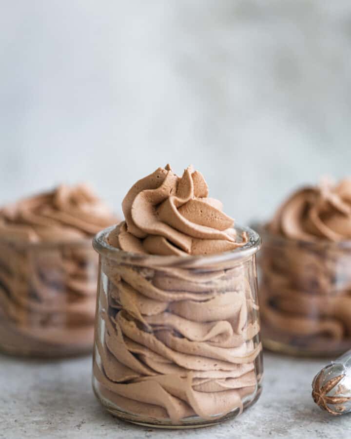 Whipped chocolate frosting in 3 small glass jars.