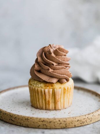 Whipped chocolate frosting piped onto a cupcake.