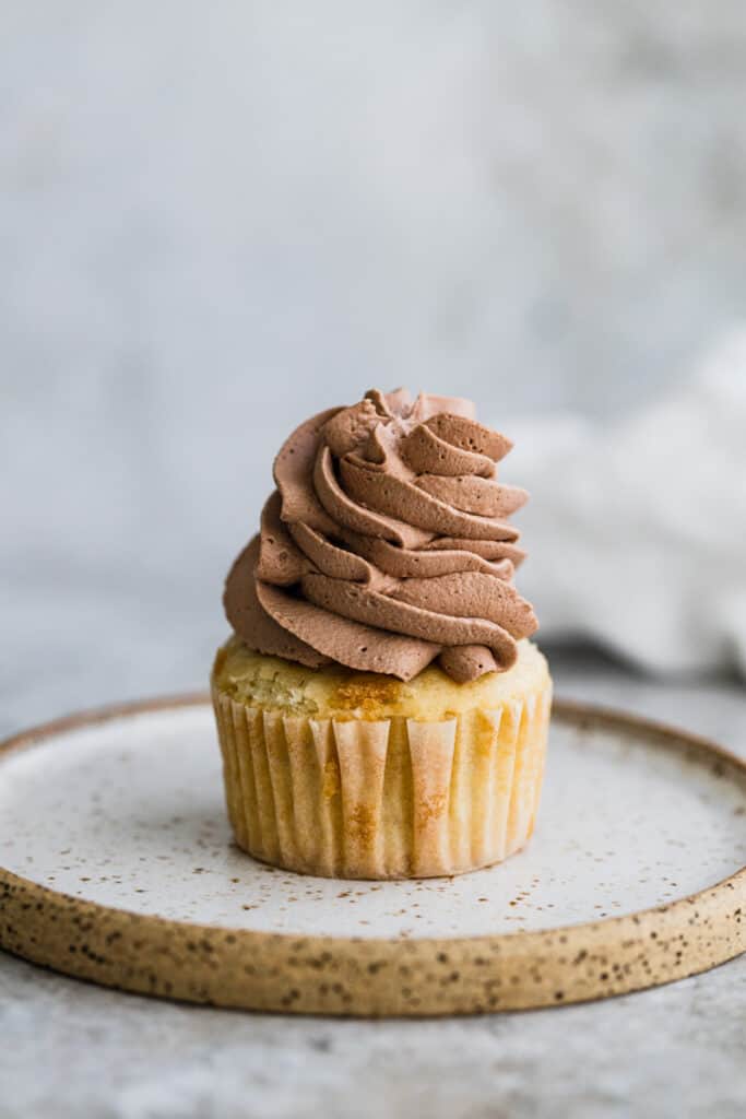 Whipped chocolate frosting piped onto a cupcake.