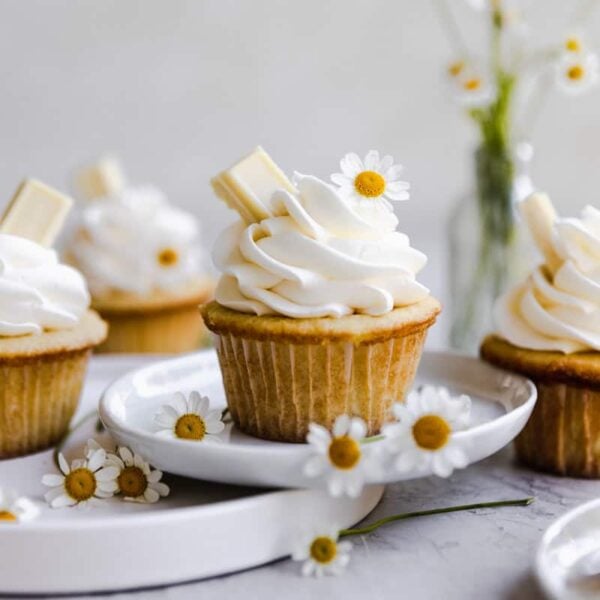 White chocolate cupcakes stacked on a few white plates.