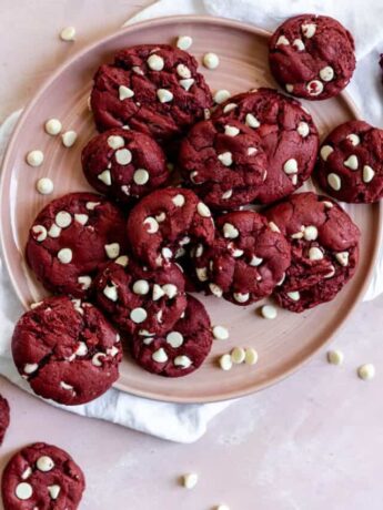 Red velvet cookies with white chocolate chips on a pink plate.