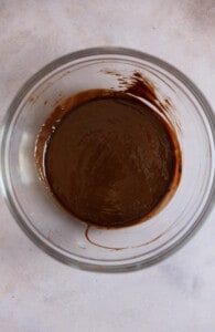 Melted chocolate in bowl on a gray surface.