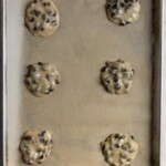 Chocolate chip cookie dough on a parchment lined cookie sheet.