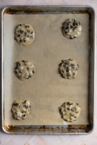 Chocolate chip cookie dough on a parchment lined cookie sheet.