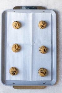 Chocolate chip cookie dough on a parchment lined cookie tray.