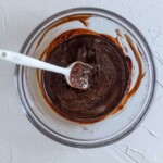 Melted chocolate in a glass bowl with a spatula.