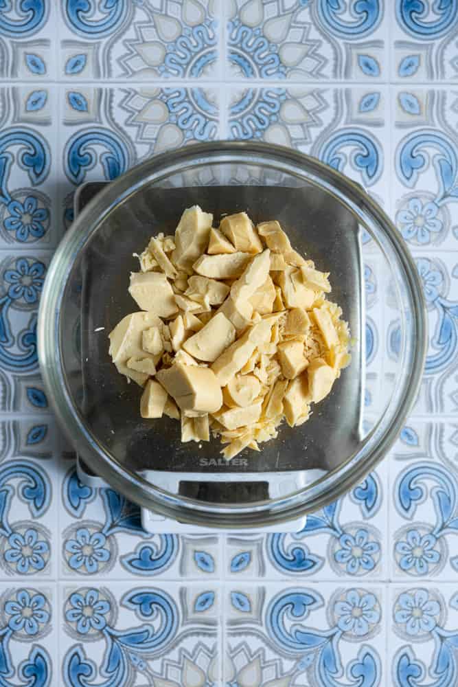 White chocolate in a glass bowl on a kitchen scale.
