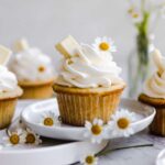 A vanilla cupcake decorated with white flowers.