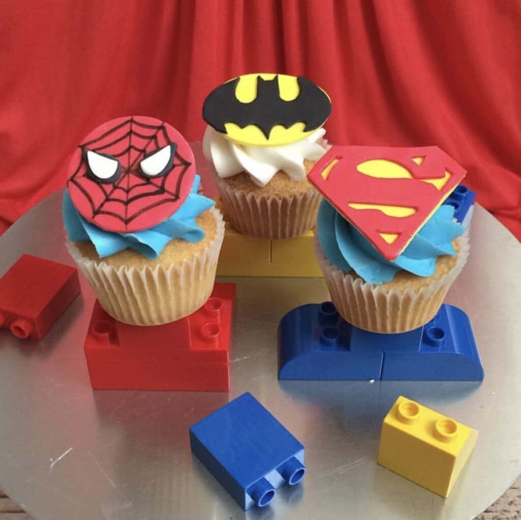 Superhero themes cupcakes on a cake stand.