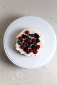 A cake layer topped with frosting and berries.
