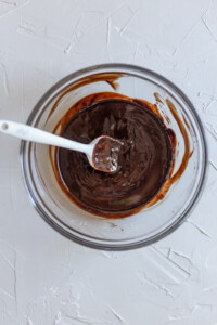 Melted chocolate in a glass bowl with a white spatula.